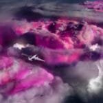 A plane flies over the tops of thunderclouds that are glowing purple.